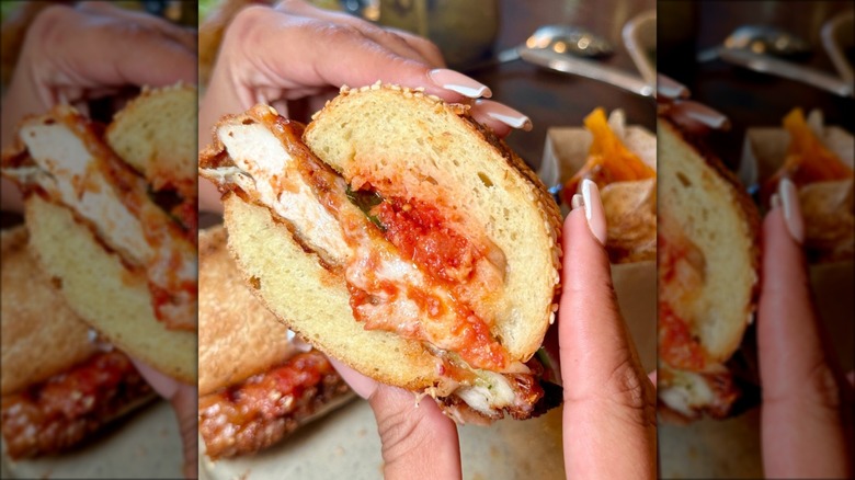 Hands holding chicken Parmesan sandwich