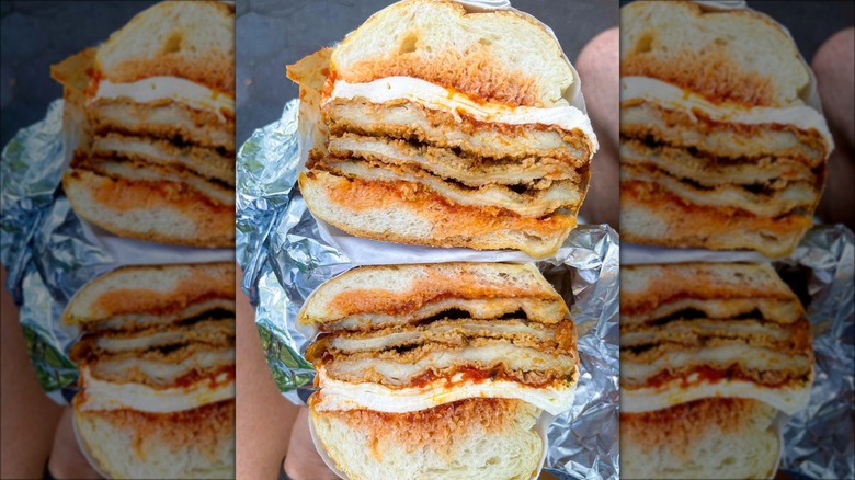 Hand holding chicken Parmesan sub in foil