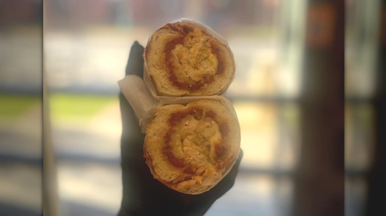 Gloved hand holding two halves of chicken Parmesan sandwich