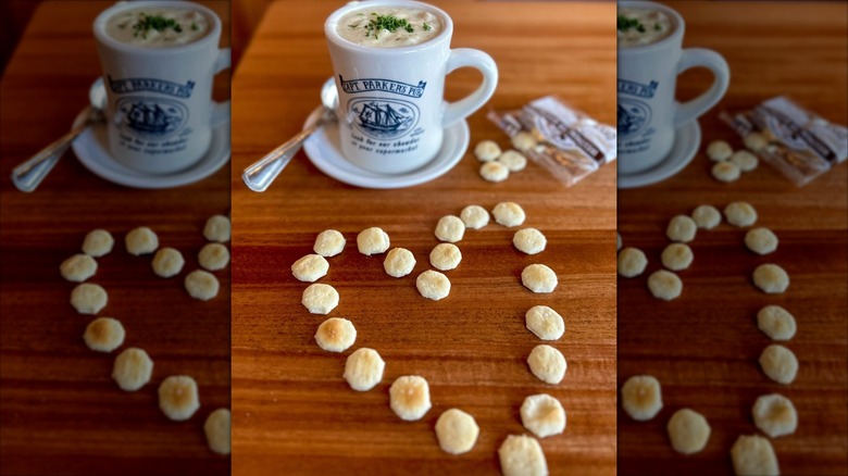Mug of Captain Parker's Pub clam chowder on a table with a heart shaped out in oyster crackers on it