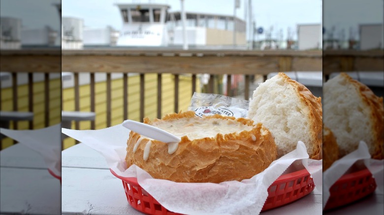 Gilbert's Chowder House clam chowder in a bread bowl with a blurred sea bay in the background