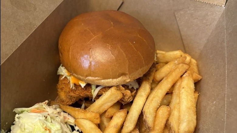 Fin & Claw Fish Sandwich with side of fries and coleslaw in a to-go container
