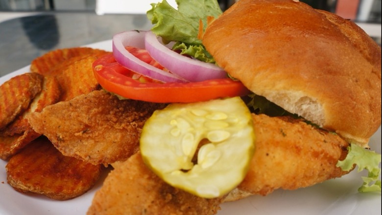 Caplinger's Fresh Catch Caplinger Sandwich with fried potatoes on a white plate