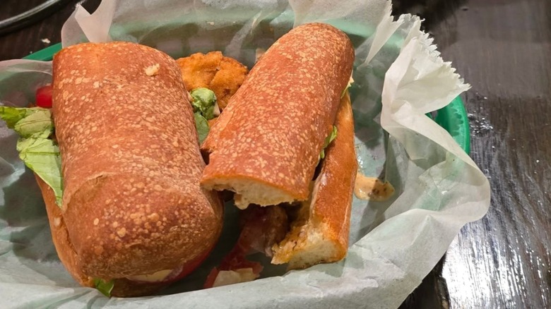 Terrebonne Po'Boys Fried Catfish Po'Boy on butcher paper in a green plastic basket