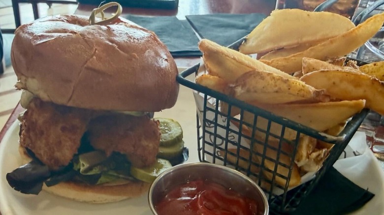 Causeway Restaurant Fried Haddock Sandwich served with fries in a metal basket and a side of ketchup in a metal ramekin on a white plate