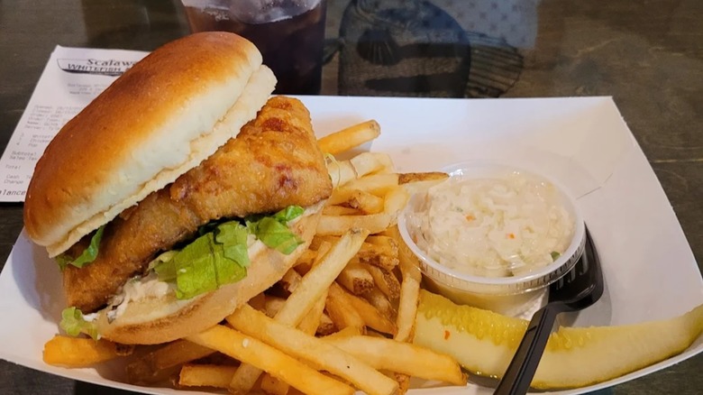 Scalawags Whitefish & Chips Fish sandwich with fries and coleslaw on a white rectangular plate