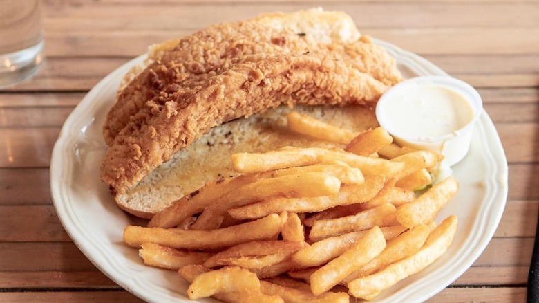 The Piccadilly at Manhattan The Famous Piccadilly Fish sandwich with side of sauce and fries on a white plate