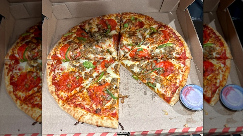 A Quik Trip pizza with meat and vegetable toppings sits in an open box