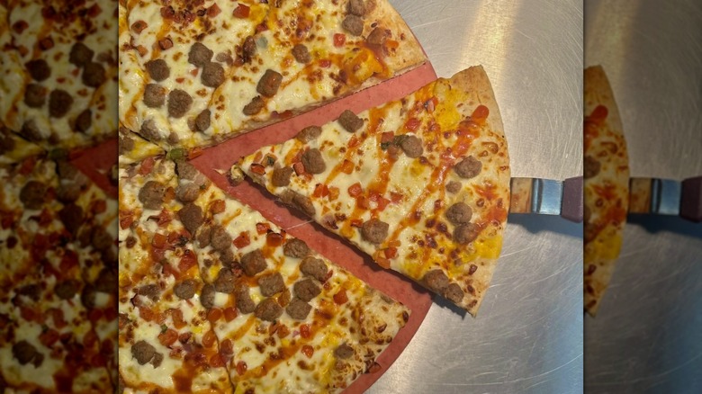 A RaceTrac taco pizza with a serving utensil under one of the slices
