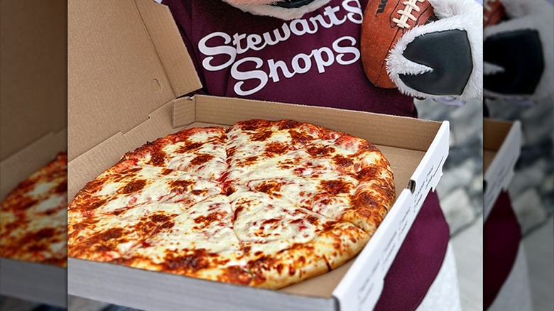 A Stewart's Shops pizza sits in a box in front of a mascot holding a football
