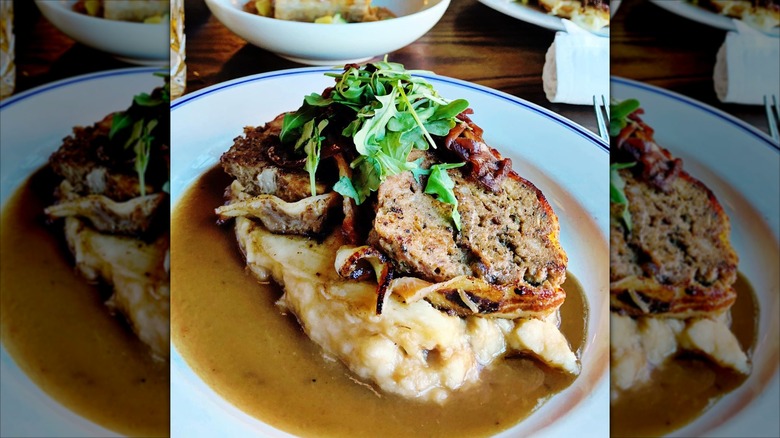 Butcher´s Union bacon wrapped meatloaf with gravy and mashed potatoes on white plate