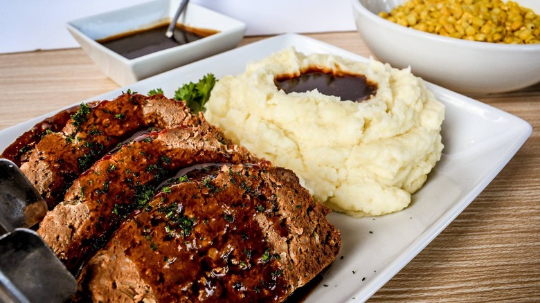 meatloaf with sides of mashed potatoes, gravy, and corn
