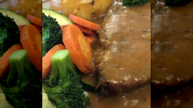 Close-up view of meatloaf and gravy with mixed vegetables