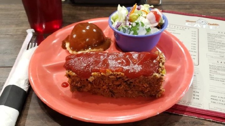 meatloaf with side salad and mashed potatoes with gravy on red plate