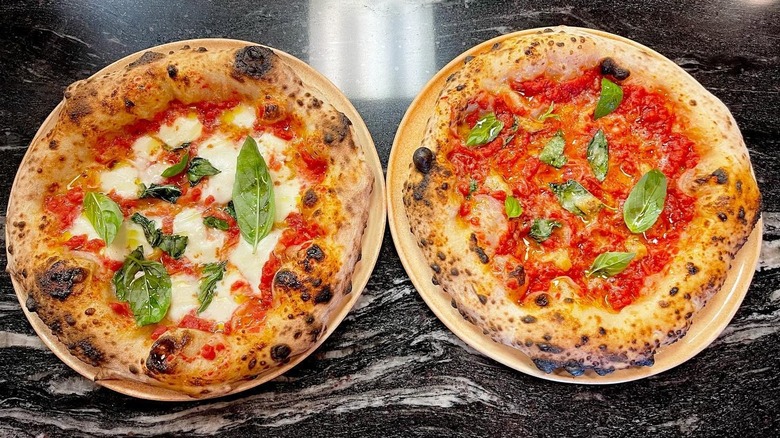 Two pizzas side by side on black surface