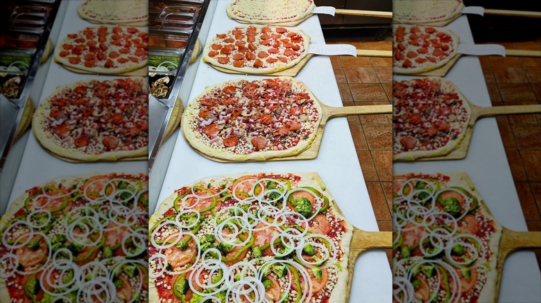 Row of unbaked pizzas
