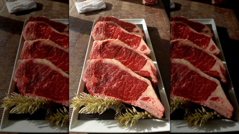 Four raw steaks on long plate
