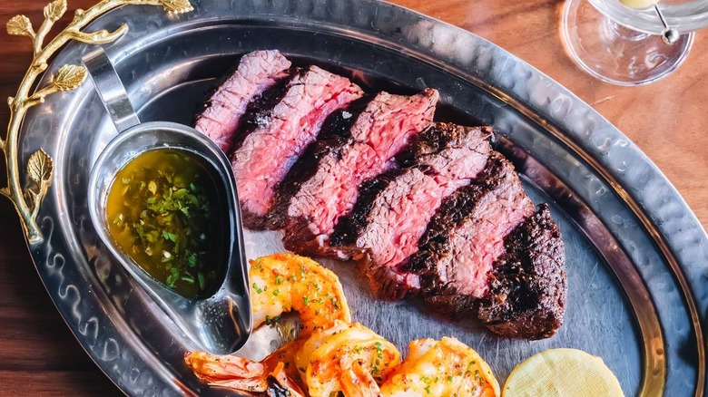 cut steak on plate with shrimp and chimchurri at A5 Steakhouse