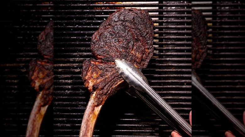 Steak being turned on grill with metal tongs at The Ruxton