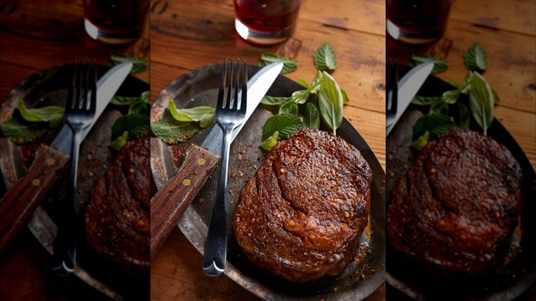 prepared steak on a plate with herbs and cutlery at Jess and Jim's