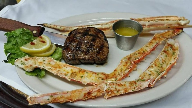 a plate of steak, crab legs and drawn butter at Beef 'n Bottle