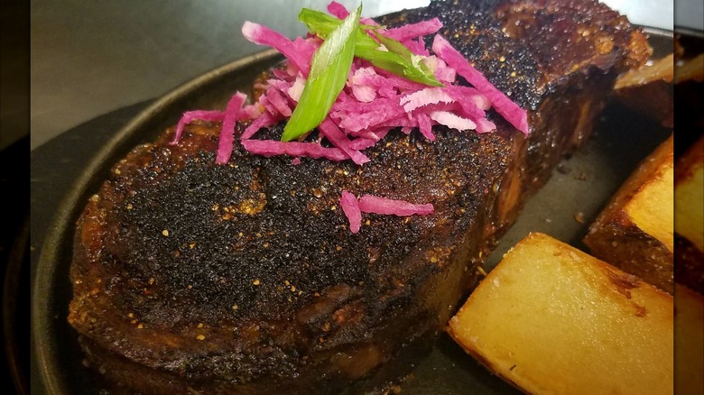 a steak topped with pickled onions at 40 Steak + Seafood