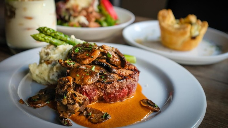 steak plated with mushrooms, asparagus, and mashed potatoes at Hoof and Vine