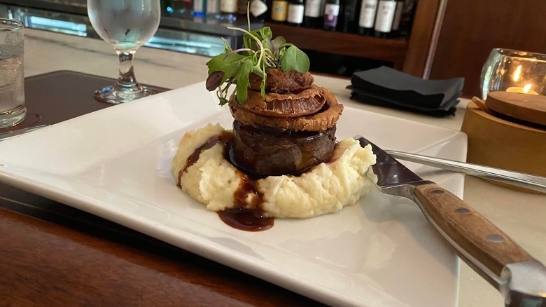 plated steak on mashed potatoes, topped with onion rings, served on the bar at E.B. Strong's