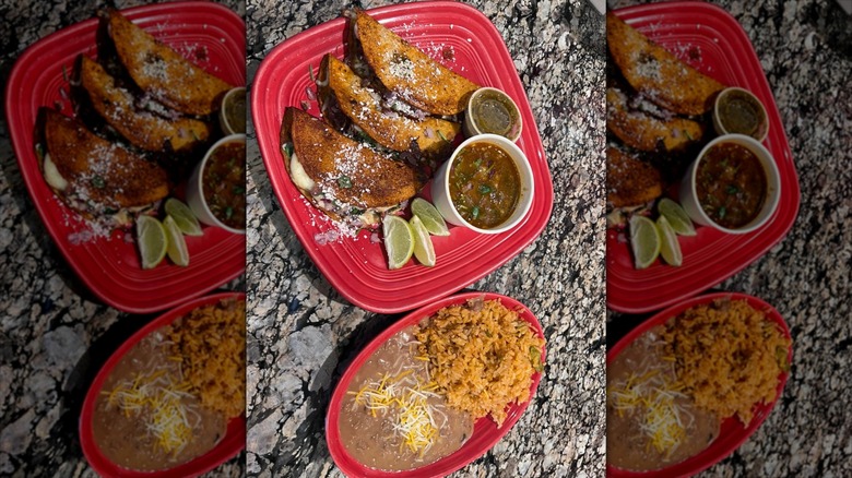 Two red plates of tacos, rices, and beans