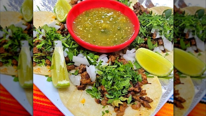Steak tacos on plate with onion, cilantro, and lime