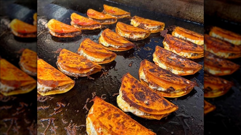 Rows of street tacos on griddle