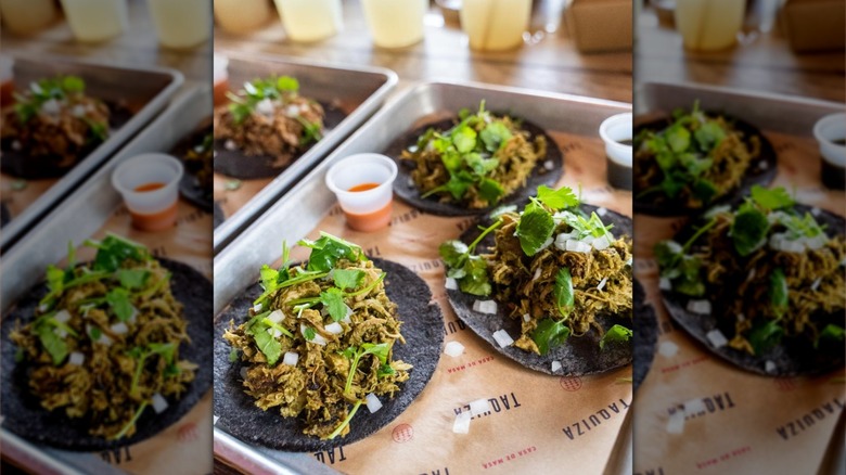 Three tacos on blue corn tortillas on tray