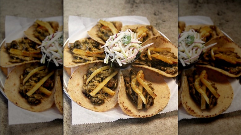 Six tacos on a plate in a circle around coleslaw