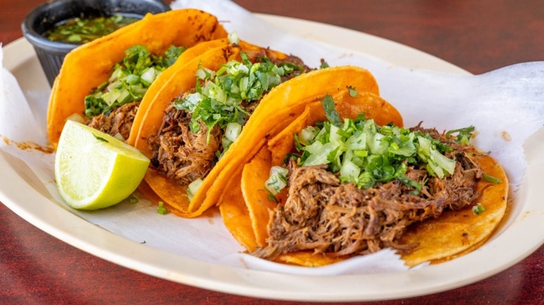 Three shredded beef tacos with toppings