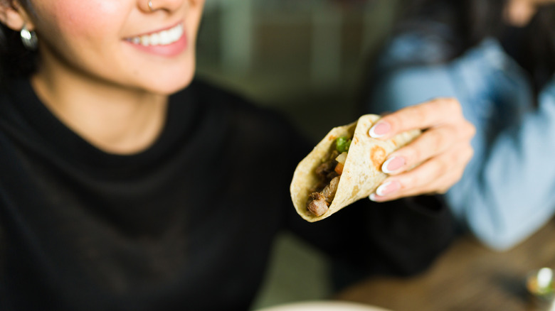Woman smiling and holding taco