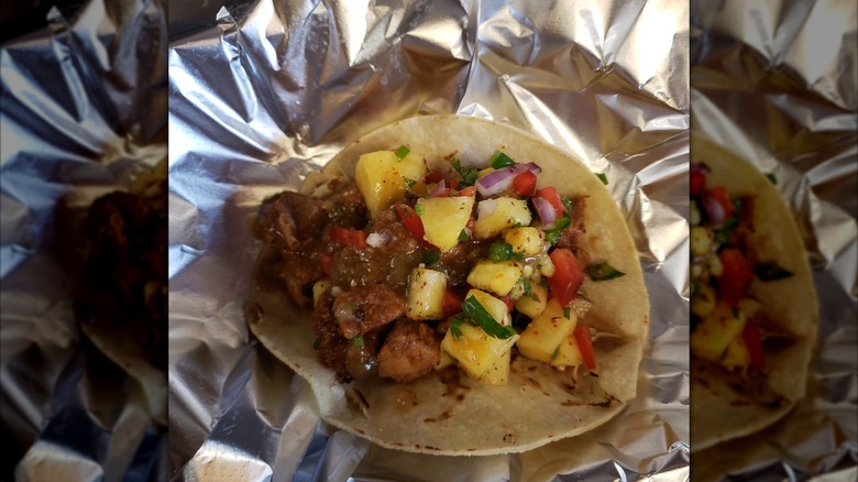 Al pastor taco on tin foil with toppings