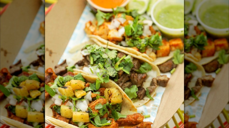A trio of tacos with cilantro, lime, and sauces