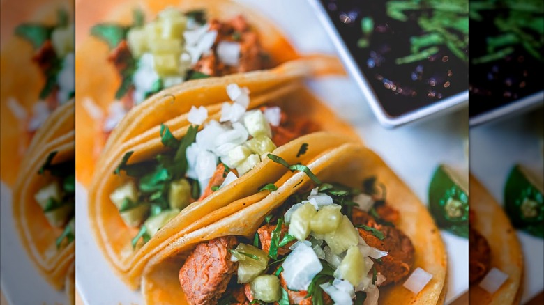 A trio of tacos topped with onions and cilantro