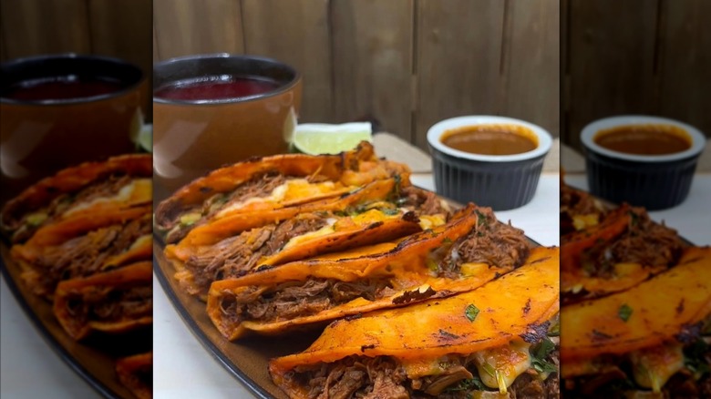 Birria tacos on a plate with sauce on the side