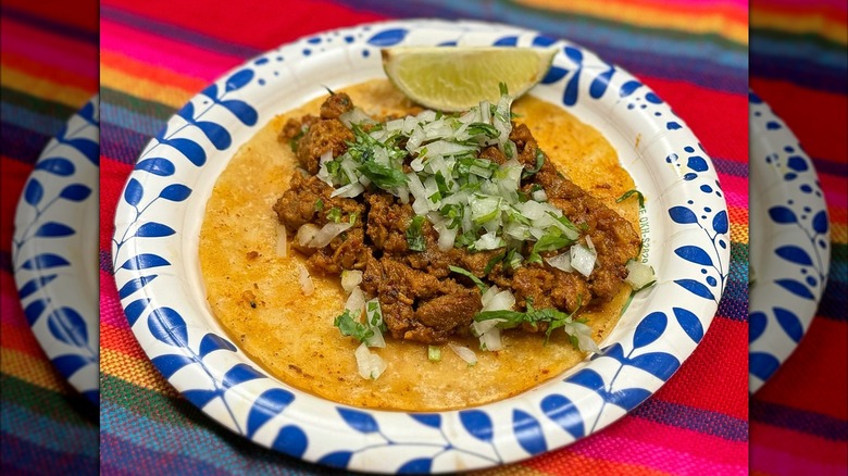 Taco with onion and cilantro on paper plate rainbow table cloth