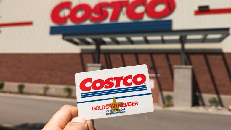Person holding Costco Gold Star membership card in front of store