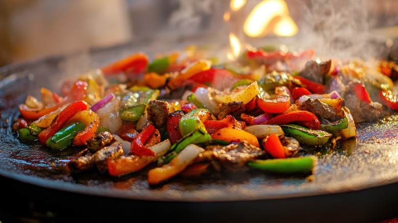 Fajitas cooking on a hot slab over a fire.