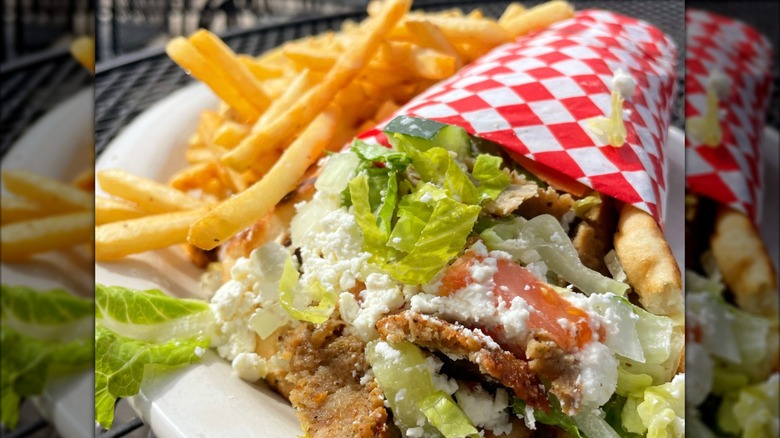 Deluxe Gyro with lettuce, feta, and cucumbers and a side of French fries on a white plate from Chef Zorba's