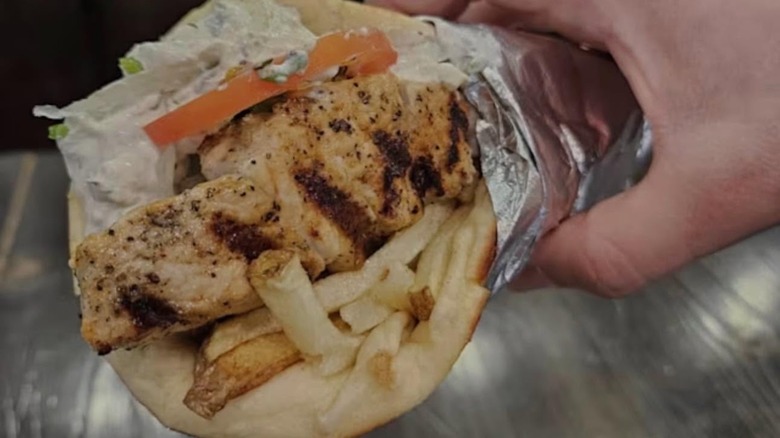 Hand holding The Souvlaki Gyro from Mitsos Greek Food & Coffee
