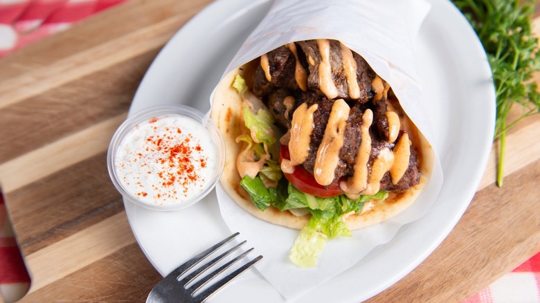 Gyro from Gyro House Mediterranean Grill on a white platter with a side of tzatziki sauce