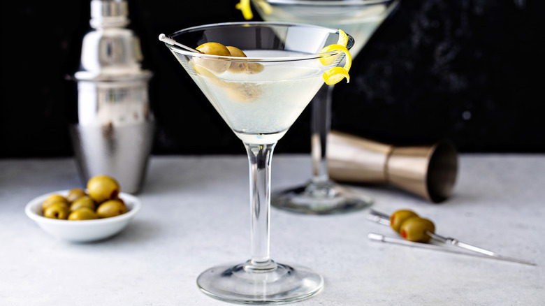 A dirty martini in a glass with olives and a twist of lemon peel