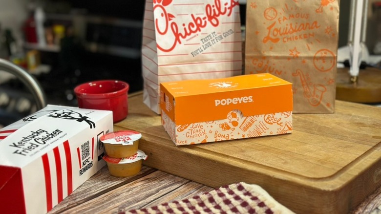 KFC, Chick-fil-A, and Popeyes takeout boxes and bags on kitchen counter