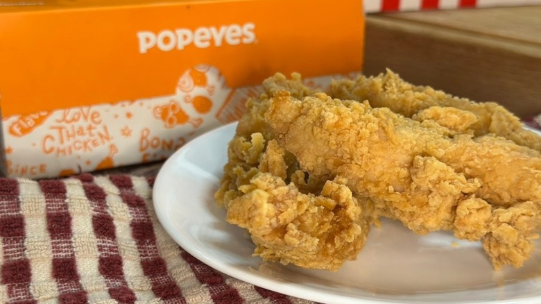 Popeyes chicken tenders on a plate next to Popeyes takeout box