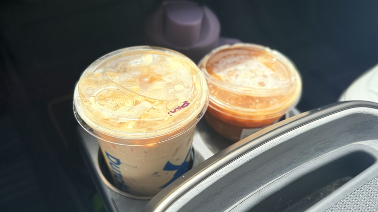 Dutch Bros Golden Eagle and Starbucks Iced Caramel Macchiato in plastic to-go cups in car cupholder
