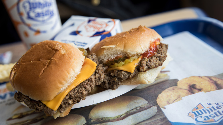 White Castle Impossible sliders on a white paper plate shown with onion rings and a drink